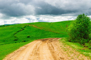 Dirt road on a mountain plateau in a mountainous area in cloudy weather