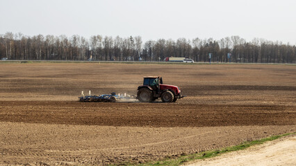 Obraz premium Red tractor is plowing a field closeup
