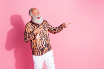 Photo of funny grandfather laugh point finger empty space tiger print shirt isolated on pink color background