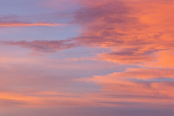 Soft pink and orange clouds blend gracefully in the evening sky, creating a dreamy atmosphere. Sunset colors mix with blue, purple, red, and yellow hues, painting a vibrant scene