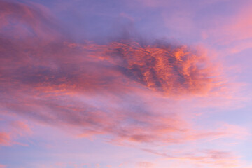 Naklejka premium Swirling pink and purple clouds in a dusky blue sky, creating a serene nature scene. The colors blend harmoniously in the twilight sky, offering a vibrant display exuding calm and beauty