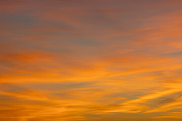 Dramatic sky with wispy clouds changing color from orange to blue during sunset, creating a warm and vibrant atmosphere