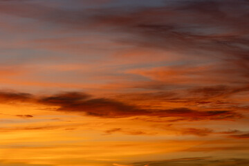 Golden hour light illuminating wispy clouds streaking across the sky, creating a vibrant and captivating atmospheric display