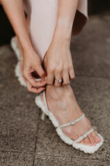 Fashion details of female hand fastening high heel shoe, elegant street women's fashion