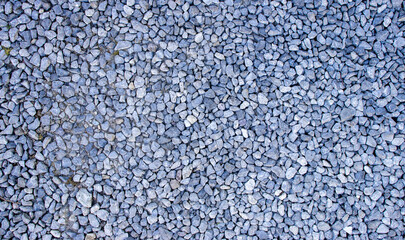 A close-up of a textured surface made of small gray stones, ideal for backgrounds or construction themes. The image provides a natural and organic feel.