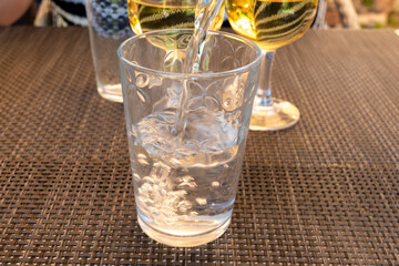 Waiter pouring mineral water from the glass bottle into a glass, food concept