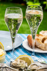 Champagne sparkling wine in glasses and oysters from Arcachon bay served on oysters farm in Gujan-Mestras, with lemon, baquette bread, butter