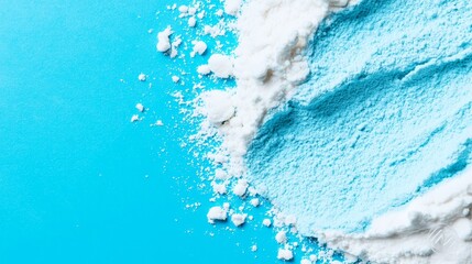 Fototapeta premium A mound of powder, half blue and half white, lies next to a toothpaste bottle on a blue countertop
