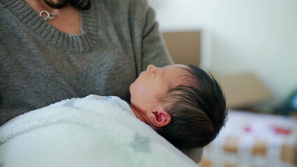 Newborn baby peacefully resting in mother’s arms, highlighting the tenderness and security...