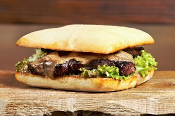 A delicious sandwich with grilled meat, lettuce, and a creamy sauce on a soft bun.