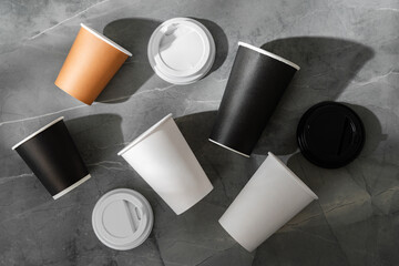 Assorted disposable coffee cups on a textured surface from different angles
