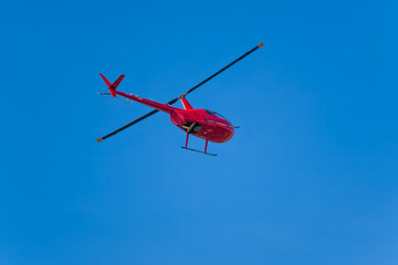 Red helicopter flies in blue sky