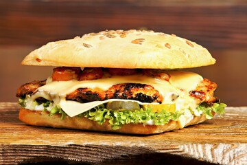 A delicious sandwich featuring grilled chicken, cheese, lettuce, and sauce on a sesame bun.