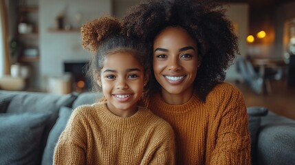 Naklejka premium A mother and her daughter smile brightly while sitting closely together on a soft couch in a comfortable living space