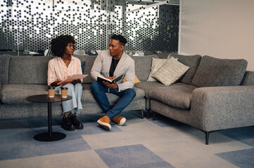 Interracial colleagues writing down in textbook business strategy.