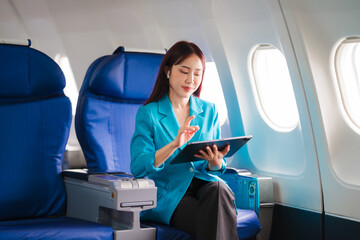 Businesswoman in the Clouds: A young Asian professional engrossed in work on a digital tablet...