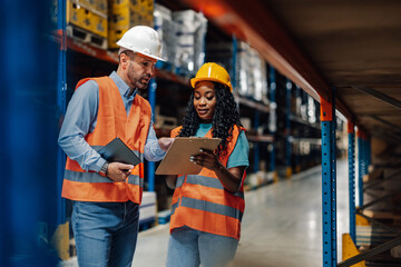 Colleagues reviewing data on clipboard in a warehouse setting.