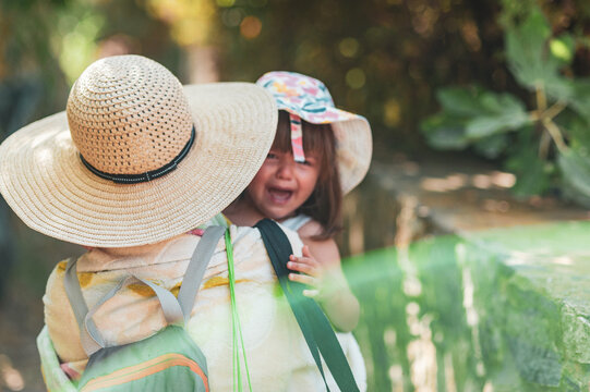 A mother is carrying a crying daughter as they go to the beach