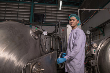Fototapeta premium Worker Checking quality or checking stock of glass bottle in beverage factory. Worker QC working in a drink water factory