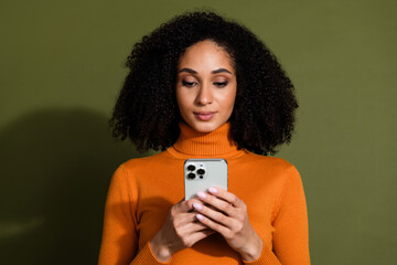 Photo of cheerful pretty lady dressed orange turtleneck texting sms modern gadget empty space isolated green color background