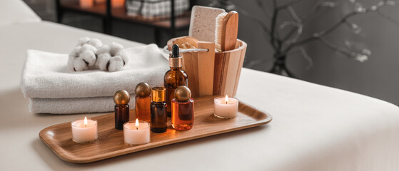 Spa composition with burning candles and cosmetic products on couch in salon, closeup