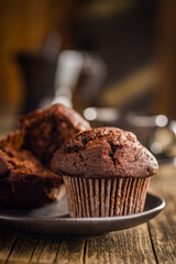 Sweet chocolate muffin cakes on plate on wooden table.