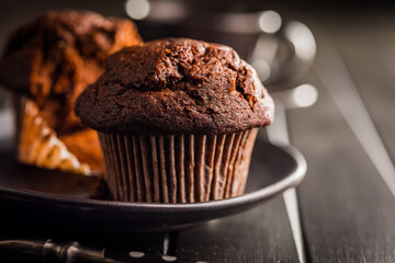 Sweet chocolate muffin cakes on plate on wooden table.