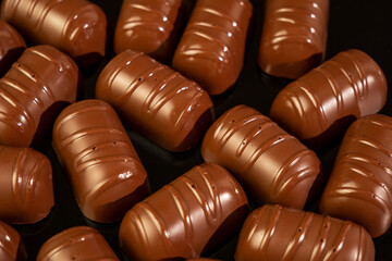 Delicious chocolates on a black background. Lots of chocolate praline. Cocoa candies made from milk chocolate