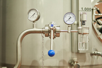 Close-up of an industrial stainless steel pressure gauge with valves and controls