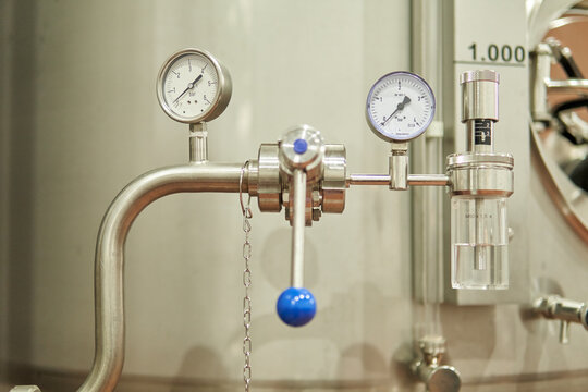 Close-up of an industrial stainless steel pressure gauge with valves and controls - Powered by Adobe