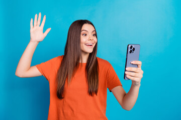 Photo portrait of attractive teen woman wave hand selfie photo dressed stylish orange clothes isolated on blue color background