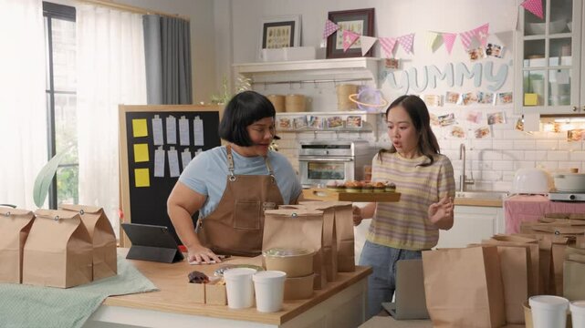 Two Asian women managing a rush of customer orders in a cloud kitchen for online food delivery service