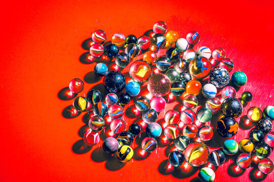 Vibrant Marbles on Red Background in Sunlight