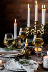Rustic Scandinavian style zero waste eco-friendly dinner table decor for Christmas or new year family celebration. Wooden table, natural elements like pine cones, fir tree branches, candles