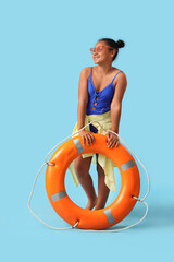 Happy African-American girl with ring buoy on blue background