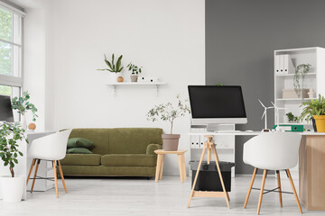 Interior of engineer's office with workplace, plants and wind turbine models