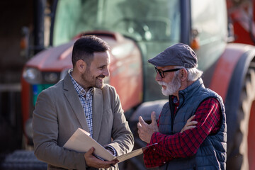 Bank agent talking to farmer on farm about contract