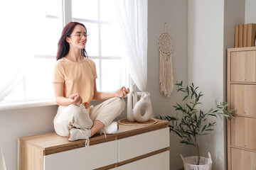 Young woman meditating on commode at home