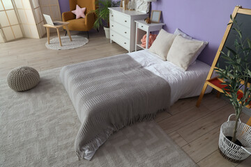 Interior of children's room with bed, commode and armchair