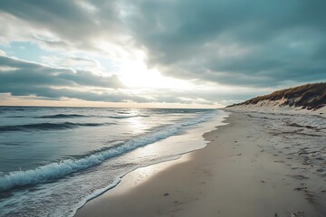 Peaceful seascape with sandy beach and cloudy sky at sunset