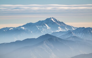 A majestic snow-capped mountain peak rising above a range of misty, blue mountains under a clear sky. Generative-Ai