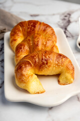 Fresh sweet and salty golden butter croissants alone and filled with ham and cheese on white sheet