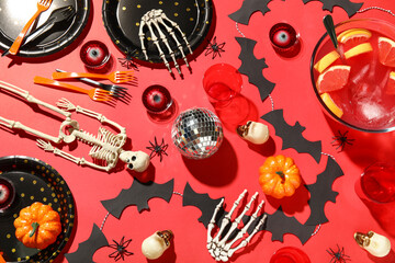 Composition with different decorations, tasty punch and tableware for Halloween party on red background