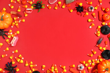 Frame made of different treats and decorations for Halloween on red background