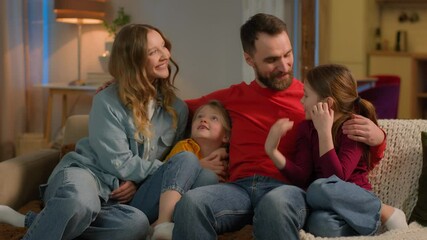 Happy friendly bonding affectionate family Caucasian parents children little girls daughters siblings on sofa evening weekend cheerful mother father kids hugging smile laugh relax home mortgage loan
