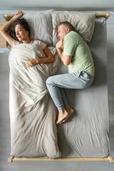 Couple sleeping in bed, woman lying under duvet her husband feeling angry and freezing, lying on...