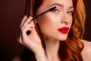 Close up photo of gorgeous attractive lady applying mascara make up isolated on brown color...