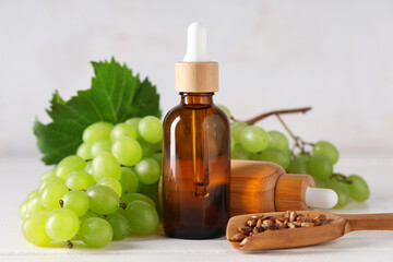 Bottles of cosmetic grape seed oil on white wooden table