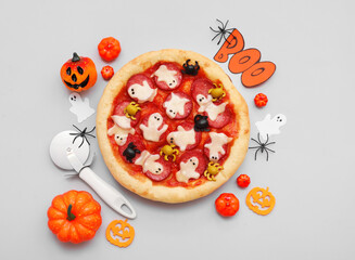 Composition with tasty Halloween pizza, cutter and different decorations on grey background