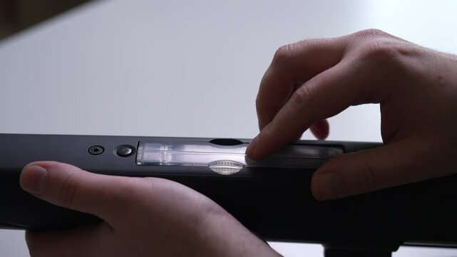 Close-up cropped shot of unrecognizable man installation transparent hop-up chamber on airsoft rifle enhances ability to adjust trajectory of bbs for improved accuracy. Shooting in slow motion.